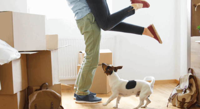 Couple moving into their new home surrounding by moving boxes and their puppy